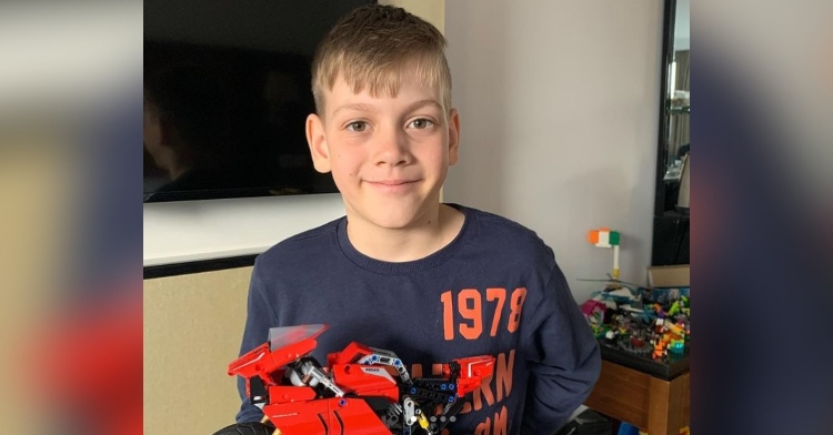 11-year-old andrey sidorov smiling as he holds a lego motorcycle that he put together.
