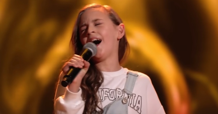 closeup of 11-year-old “the voice kids” contestant, georgia, holding the mic with one hand as she closes her eyes and passionately sings “the house of the rising sun” for her audition.