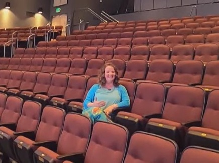 theater teacher toni butler smiling as she sits in a chair in her school's theater.