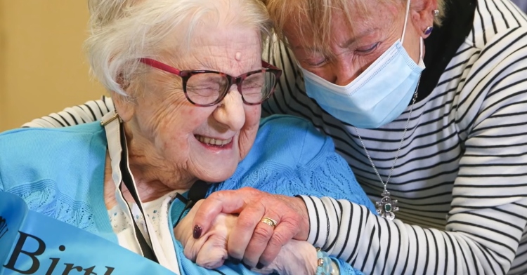 closeup of gerda cole and sonya grist as they embrace with their eyes closed.