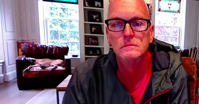 scott van pelt of espn sitting at a desk in his living room as his dog, otis, lays on a chair in the background.
