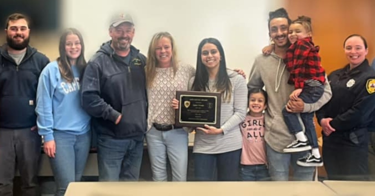 a line of 9 people gathered for a photo as sophia receives her life saving award.