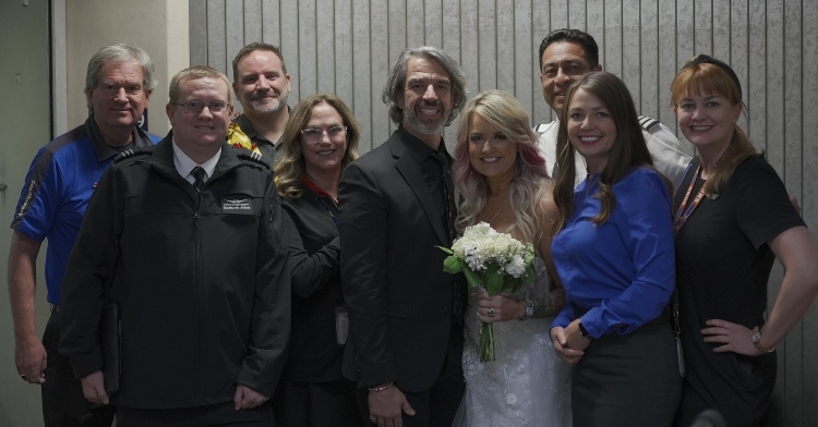 pam and jeremy salda smiling as they pose with southwest airline employees after getting married on one of their planes.
