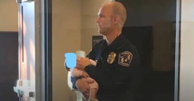 officer robert lofgran holding a woman’s baby at the west jordan police department.