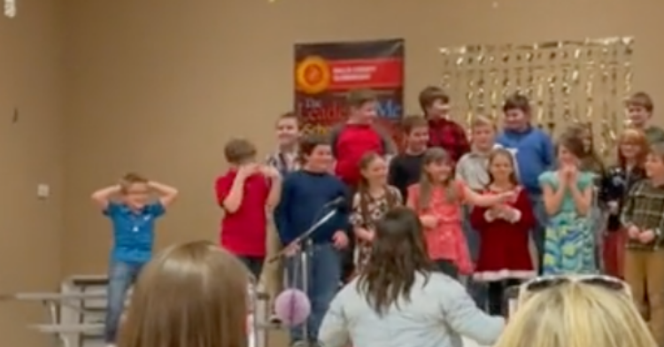 9-year-old doing his own dance moves while performing with his classmates at a school play