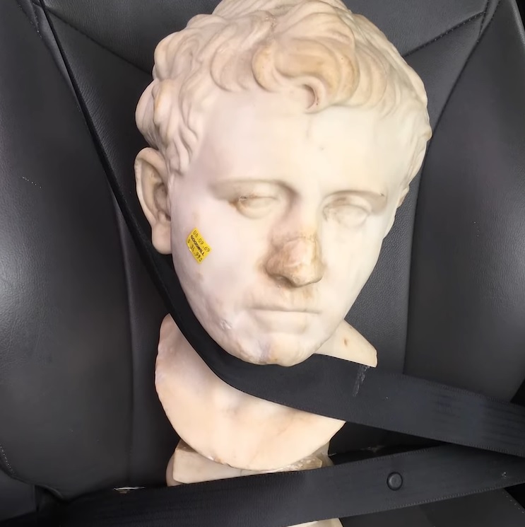 roman bust buckled into a car