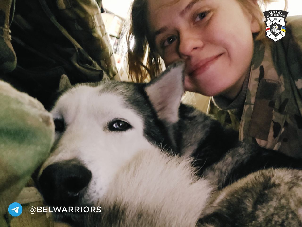 ukrainian solider smiling as she takes a selfie with a husky named nessie.