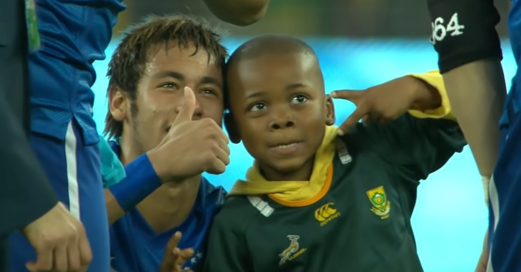 brazilian footballer neymar giving a thumbs up as he smiles and poses with 7 year old ayo who is giving a peace sign.