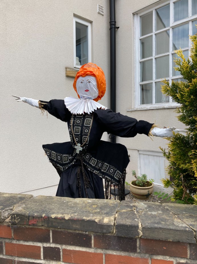 scarecrow queen with orange hair and a fancy black dress.