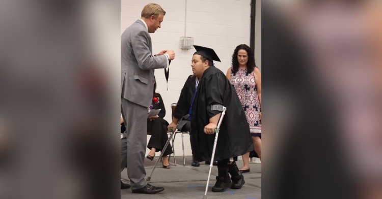 sebastian thome using crutches to walk across the stage at his high school graduation.