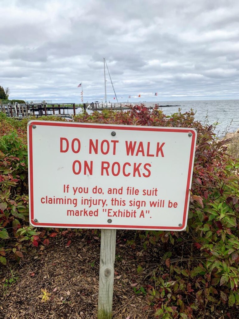 sign reading "DO NOT WALK ON ROCKS If you do, and file suit claiming injury, this sign will be marked 'Exhibit A'"