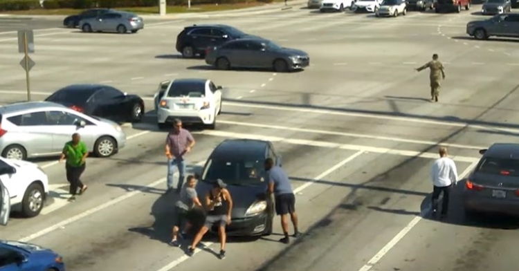 eight people surrounding a car who's driver is unconscious.