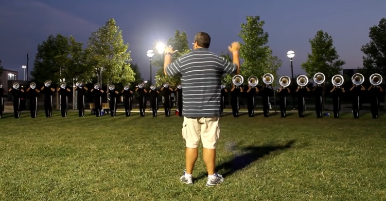 view from behind of the blue devils marching band director as he directs the brass warm-ups before the drum corps international championship in august 2010.