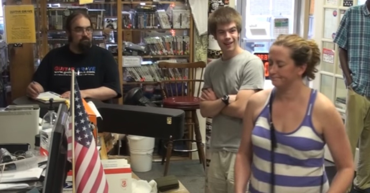 young man and guitar grave employee looking surprised at a woman named judy who just offered to pay for the young man’s guitar.