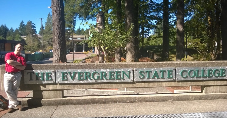Dylan Keuhl standing in front evergreen's state college sign
