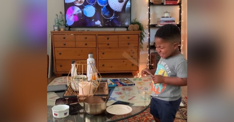 josiah passionately playing the drums on a coffee table as he copies a drummer playing on tv.