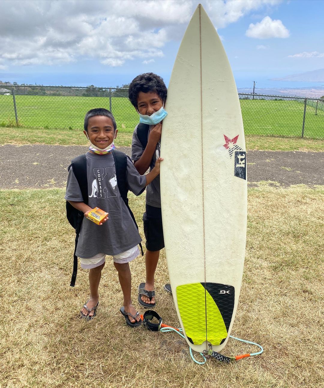 2 kids smiling with surfboard