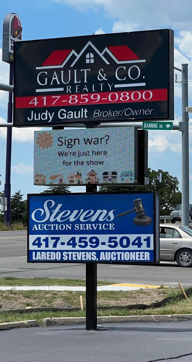 realty group sign that says: "sign war? we're just here for the show"