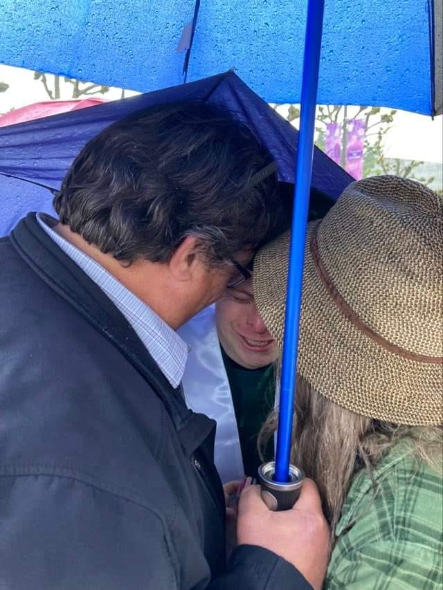 Dylan Keuhl crying under an umbrella with his parents.