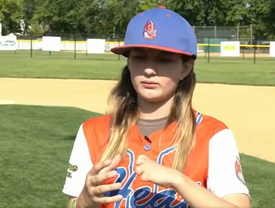 zoe wood talking about her limb difference as she stands out on a baseball field and shows off her hands.