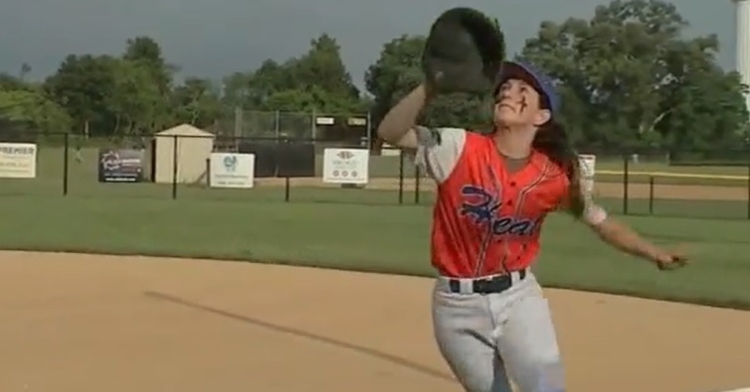 zoe wood during a baseball game. she's looking up as she runs, hand with a baseball mit on it in the air as she readies to catch the baseball.