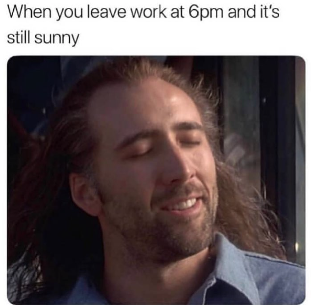a meme that says "when you leave work at 6pm and it's still sunny." and a picture of nicolas cage with long hair and the sun on his face.
