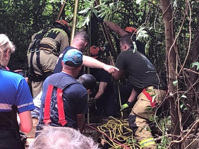 firefighters work to rescue dog that fell into deep well.