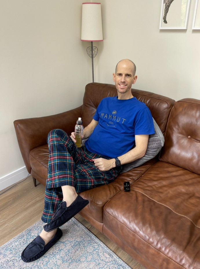 gareth smiling as he wears pajamas, sits on a leather couch, and holds a drink in his hand.