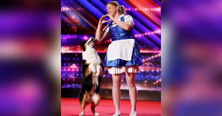 christine elizabeth berczes smiling and making a heart with her hands as she performs with her dog, meredith, on the “america’s got talent” stage.