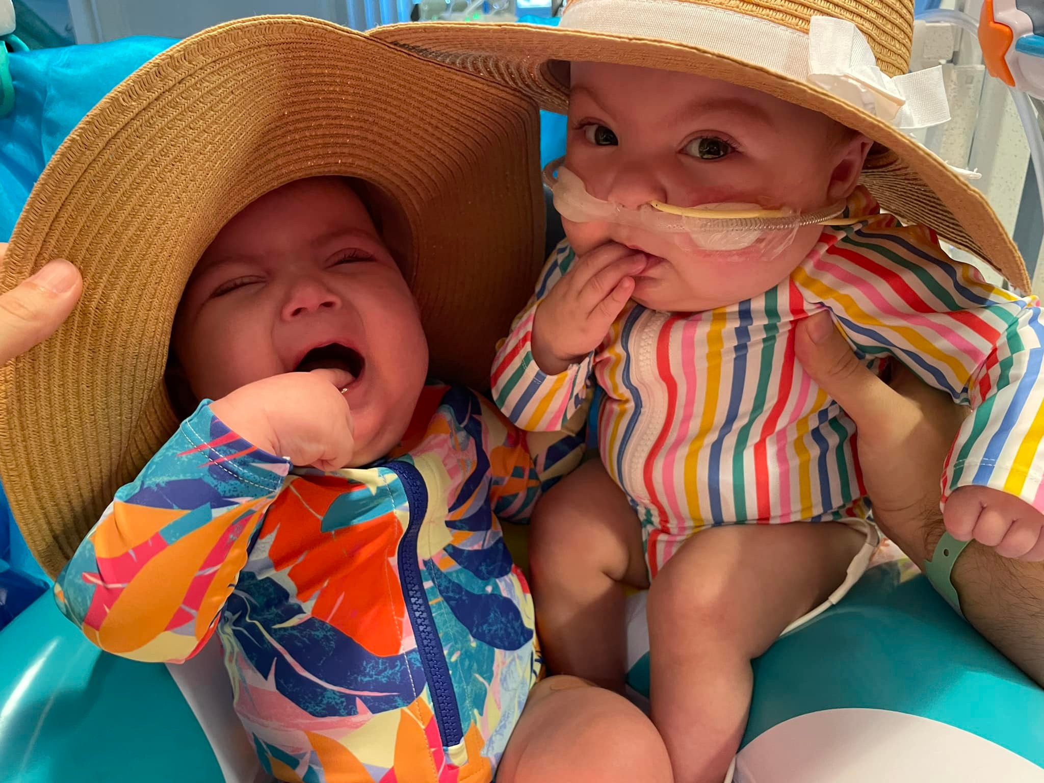 Babies Charlotte and Olivia Valliere wearing sun hats and bathing suits