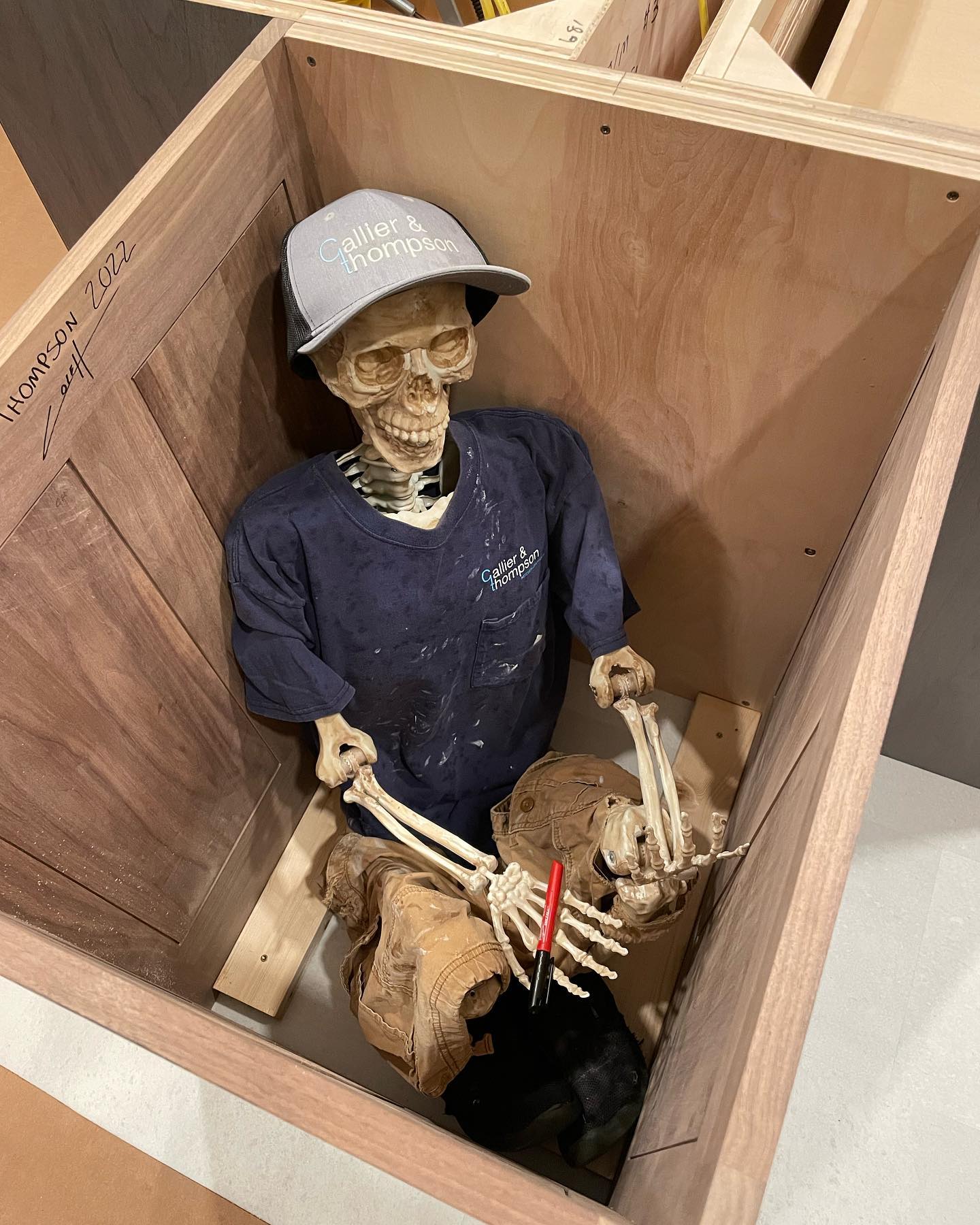 fake skeleton wearing clothes inside a kitchen cabinet