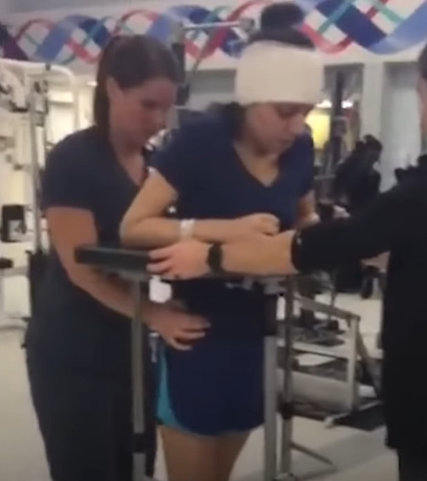 dr. claudia martinez being assisted as she tries to learn to walk again in physical therapy after stroke. 