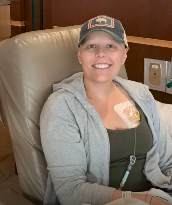 Gretchen Baldwin smiles while wearing a baseball cap to hide hair loss during cancer treatments.