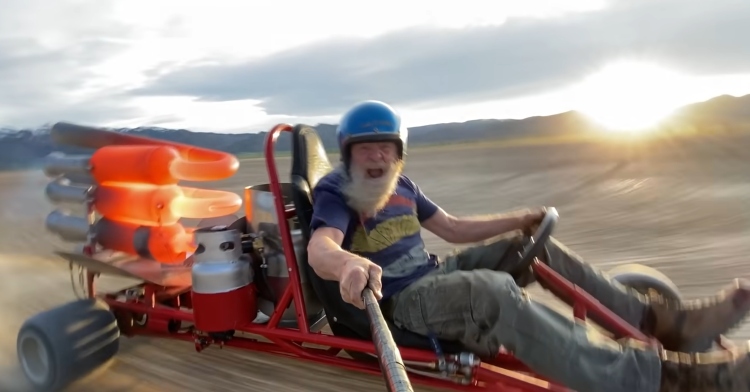 Robert Maddox drives homemade jet-powered go kart through Utah desert while sun sets behind him.
