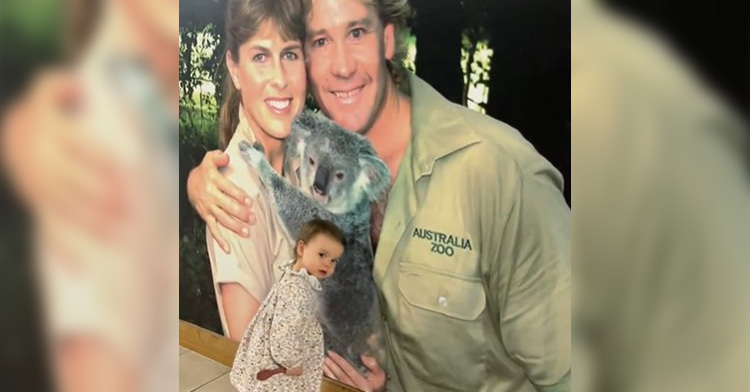 grace warrior looking back as she stands in front of a mural of terri and steve irwin holding a koala.
