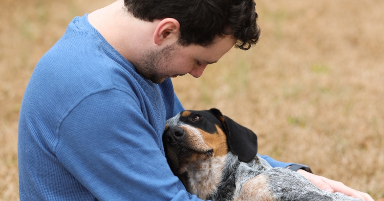 man cuddling dog in his lap