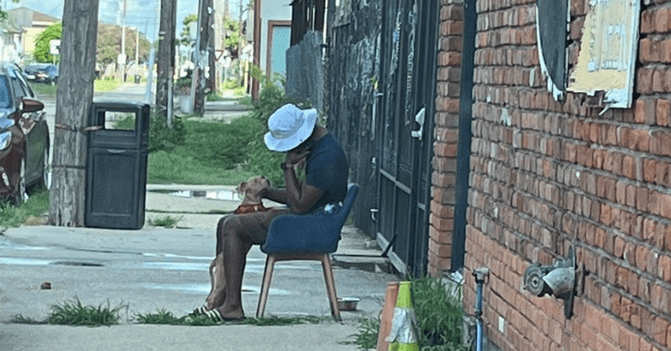 New Orleans teacher sitting on a chair outside of a rescue center with his puppy.