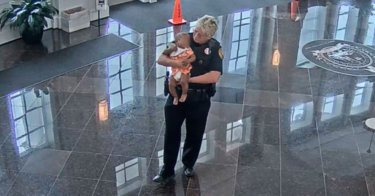 officer michelle johnson holding a baby, who's face has been blurred, as she works inside the duluth municipal court in georgia.