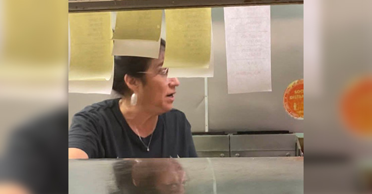 sylvia arredondo’s mom in a denny’s kitchen, looking away as she talks to someone. customers’ orders on slips of paper can be seen hanging near her.