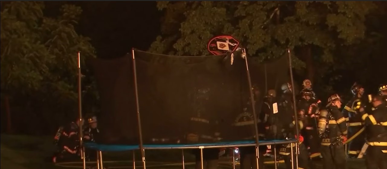 the trampoline falon o'regan used to help people in his apartment escape the fire. a group of firefighters stands nearby. 