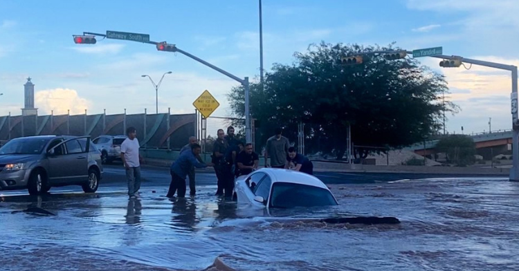 a group of good samaritans and firefighters working together trying to pull woman out of her car slowly falling into a sinkhole.