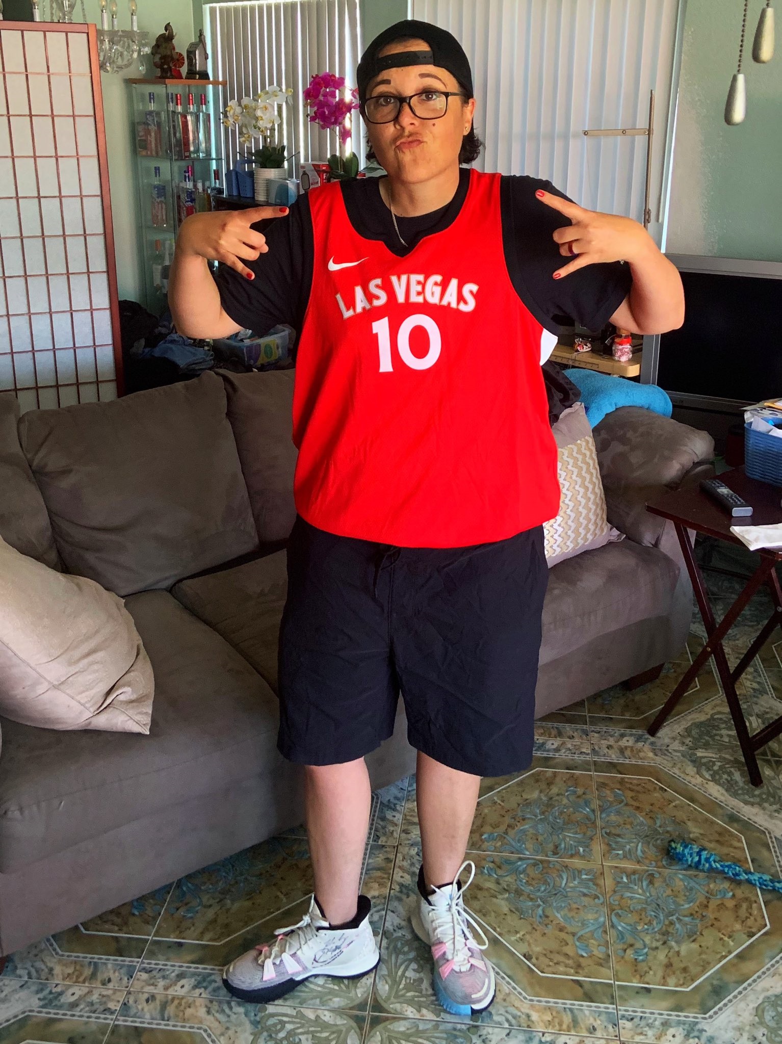 WNBA fan Ashleigh Ahrens posing in a jersey while standing in a living room.