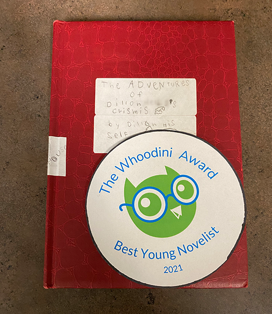 Dillon Helbig's Whoodini book with the Whoodini Award for Best Young Novelist 2021 placed on top of it.