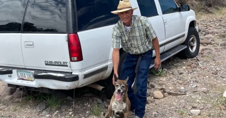 Mario Castro stands with his dog Zoe in front of white Chevy SUV