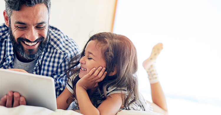 man reading a book to his daughter while smiling