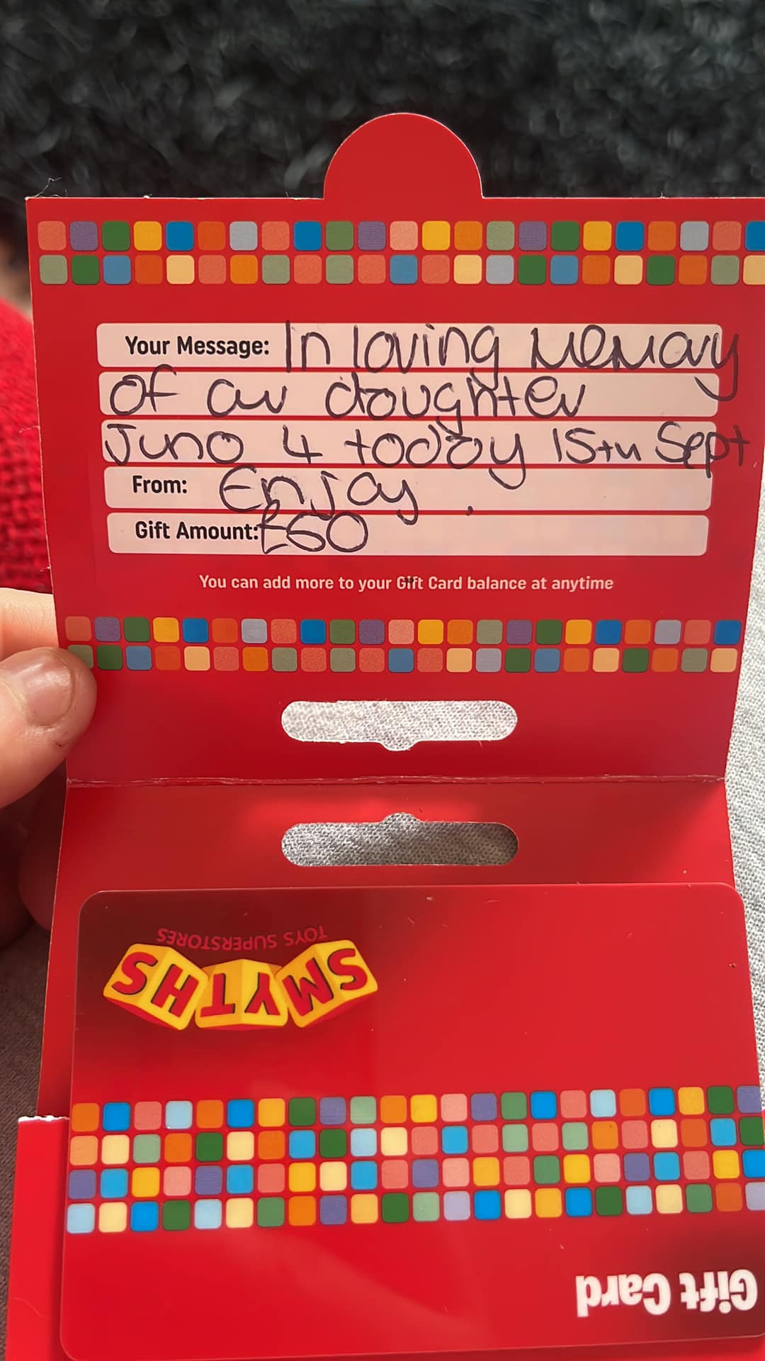 gift card from smyths toys superstores with a message that says: "in loving memory of our daughter juno 4 today 15th sept. Enjoy" and gift amout: 50 euros.