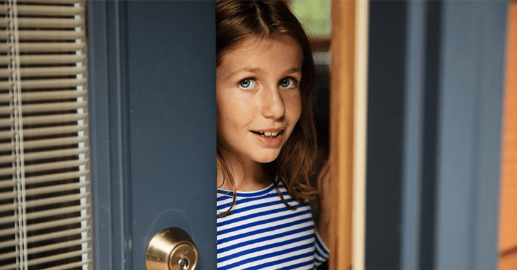 little girl opening the front door of her house and looking out