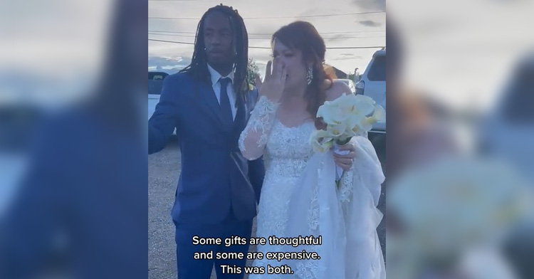 groom in dark blue suit stands next to his bride who is wiping away tears. the image is captioned "some gifts are thoughtful and some are expensive. this was both