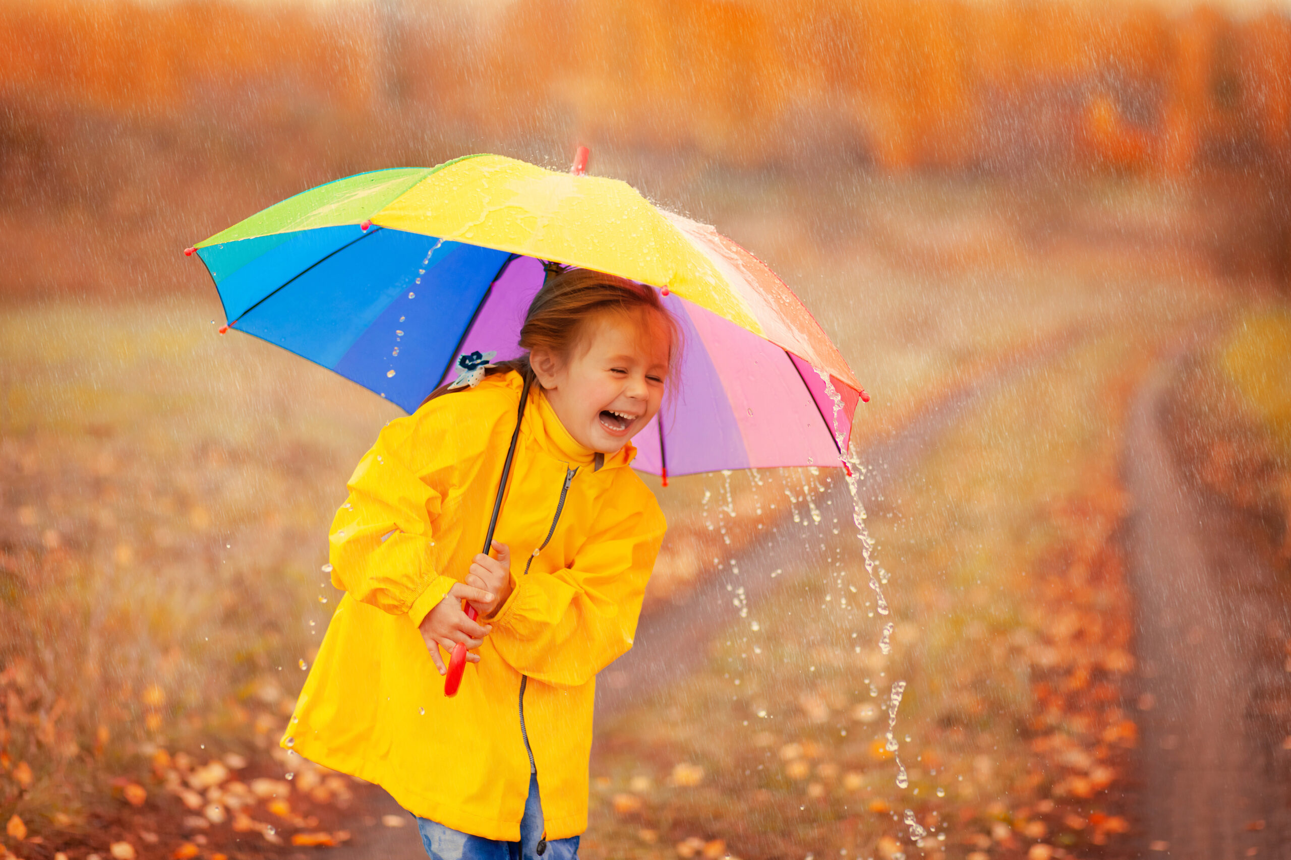 happy girl with rainbow umbrella in autumn park