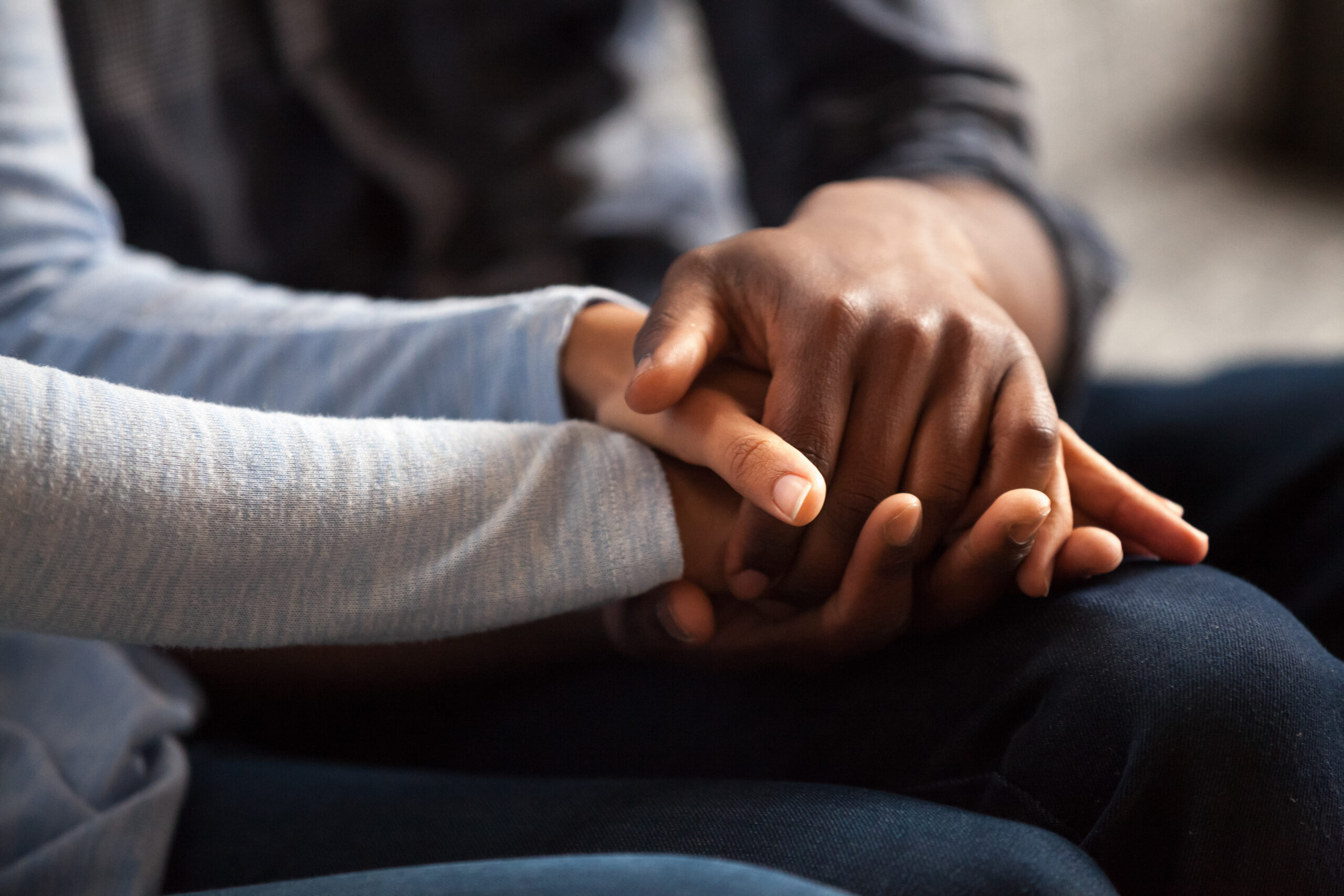 Close up of a woman and man in love sitting on couch two people holding hands. 